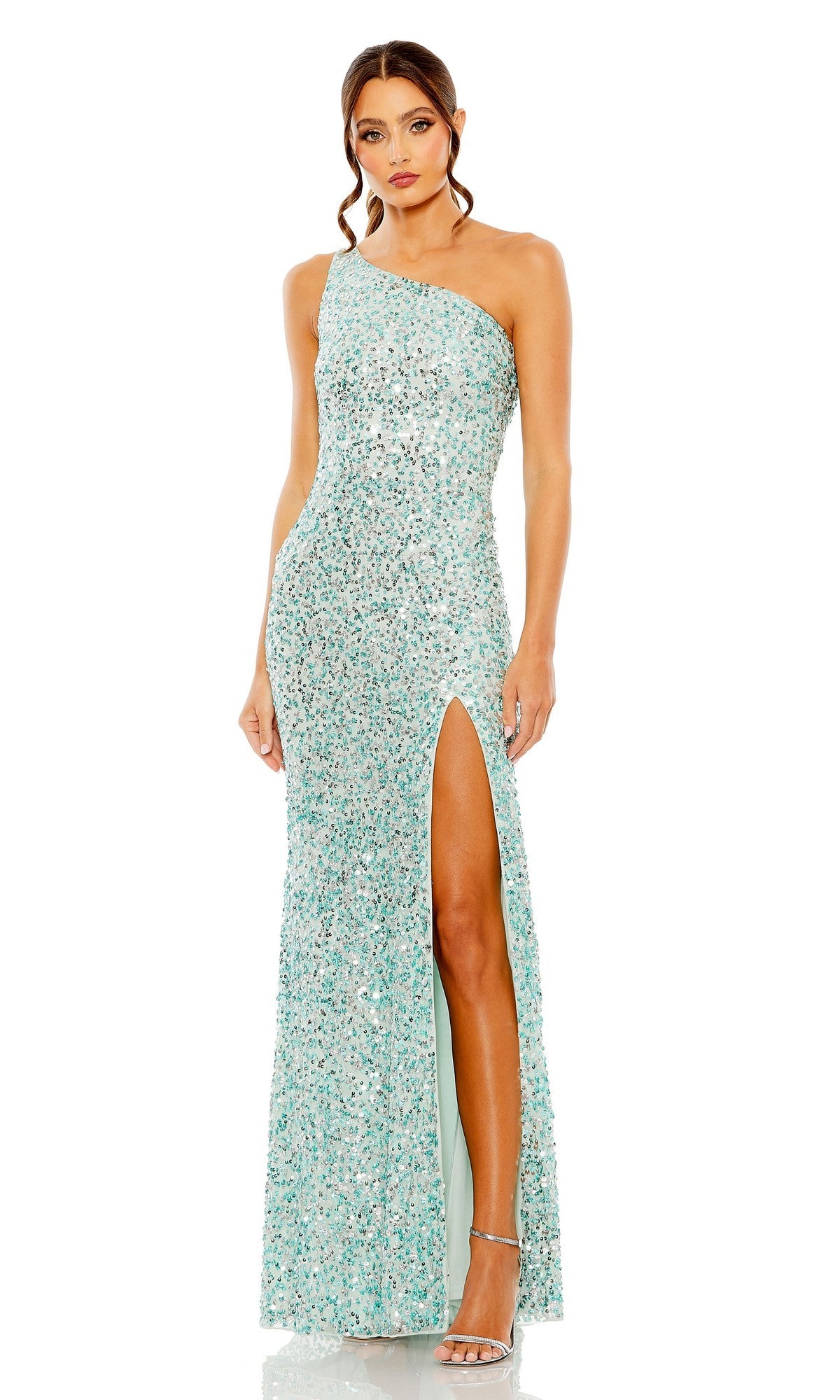 A woman faces forward in an aqua Mac Duggal 10729 long prom dress featuring a one-shoulder sequin design, a thigh-high slit, and silver high-heeled sandals.